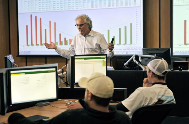 Professor talking in front of a presentation and students